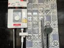 Modern bathroom wall with patterned tiles and electric shower system
