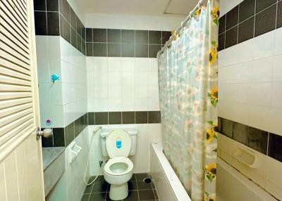 Compact bathroom with shower curtain and tiled walls
