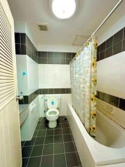 Compact bathroom with shower curtain and tiled walls