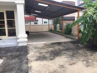 Spacious driveway in front of a residential building with carport and tropical foliage