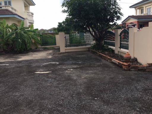 Paved driveway of a residential property with fencing and greenery