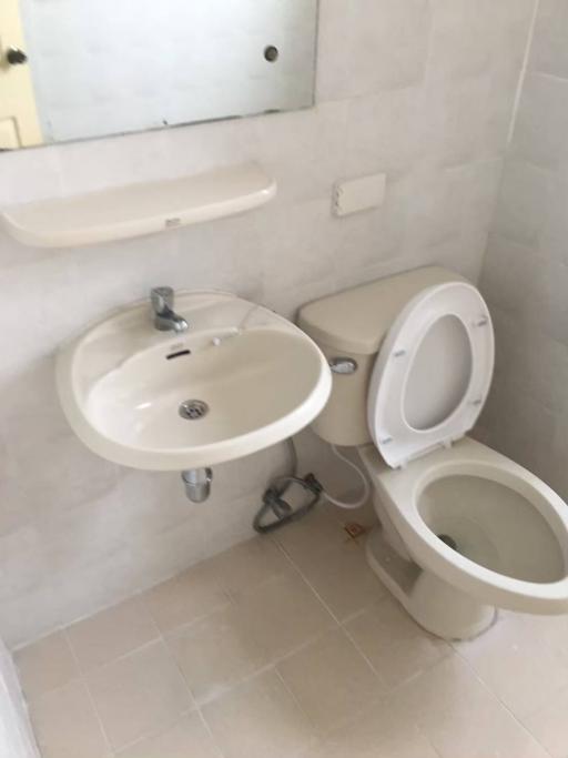 Compact bathroom with white fixtures including a sink and toilet