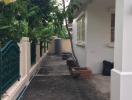 Side path of a residential building with garden fencing and greenery