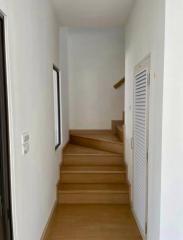 Bright hallway with wooden stairs and white doors