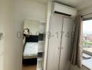 Compact bedroom with modern furnishings, including a mirrored wardrobe and an air conditioner