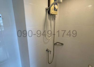 Compact bathroom with electric shower and white tiles