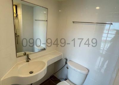 Modern bathroom with white fixtures, including sink, toilet, and mirrored medicine cabinet