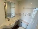 Modern bathroom with white fixtures, including sink, toilet, and mirrored medicine cabinet