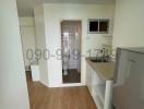 Compact modern kitchen space with wood flooring and natural light