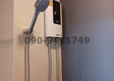 Modern wall-mounted electric shower unit in bathroom with grey tiles