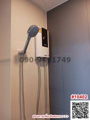 Modern wall-mounted electric shower unit in bathroom with grey tiles