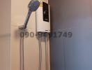 Modern wall-mounted electric shower unit in bathroom with grey tiles