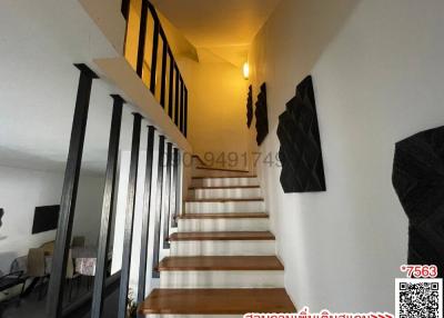 Modern staircase with wooden steps and black metal railings leading to the upper level of a house