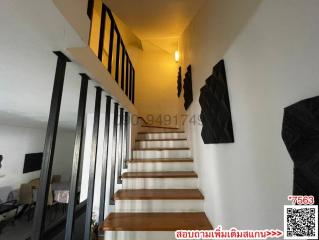 Modern staircase with wooden steps and black metal railings leading to the upper level of a house