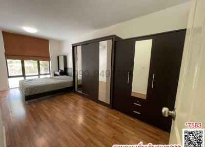 Spacious bedroom with large bed, wooden flooring, and ample closet space