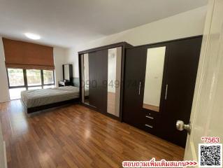 Spacious bedroom with large bed, wooden flooring, and ample closet space