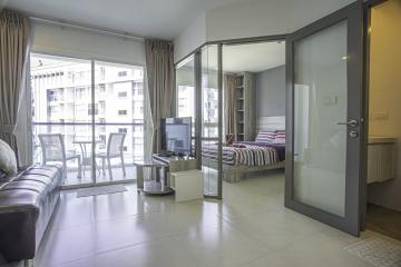 Modern apartment interior with open plan living space, showing living room, bedroom, and balcony