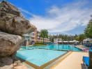 Sunny outdoor pool area with loungers, landscaping, and adjacent building