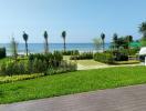 Spacious beachfront garden with lush grass, wooden deck, and ocean view