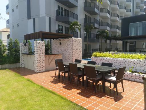 Spacious outdoor patio with dining furniture and pergola adjacent to a residential building