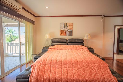 Spacious bedroom with large bed, hardwood floors and balcony access
