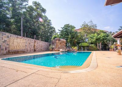 Bright and inviting outdoor pool with stone wall and lush greenery