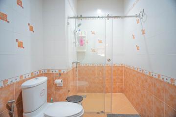 Brightly lit bathroom with shower enclosure and orange tiles
