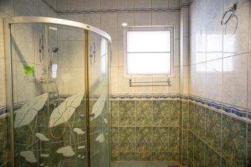 Bright bathroom with glass shower cabin and tiled walls