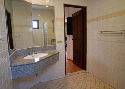 Spacious tiled bathroom with a granite countertop sink and open door
