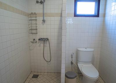 Compact bathroom with white tiling, shower, and toilet