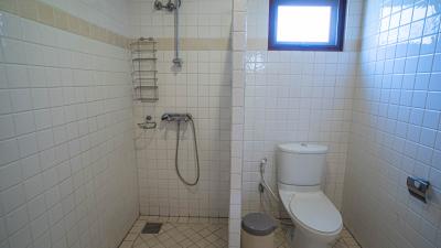 Compact bathroom with white tiling, shower, and toilet