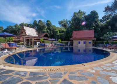 Elegant outdoor swimming pool surrounded by lush greenery and cozy poolside seating
