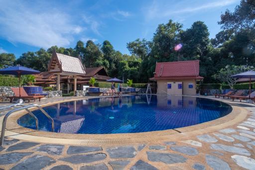 Elegant outdoor swimming pool surrounded by lush greenery and cozy poolside seating