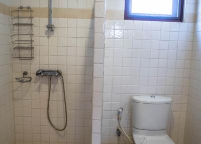 Compact bathroom with white tiles and natural light