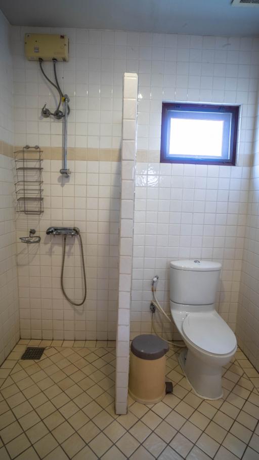 Compact bathroom with white tiles and natural light