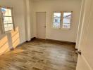 Spacious bedroom with wood flooring and natural light