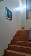 Warmly lit staircase with wooden banister and framed artwork on the wall