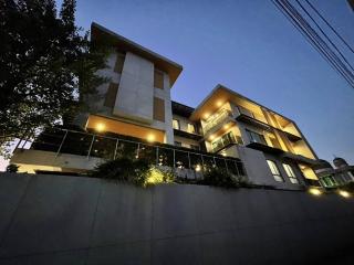 Modern multi-story residential building exterior at dusk with illuminated balconies