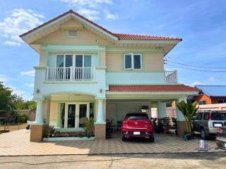 Two-story residential house with carport and balcony under a clear blue sky