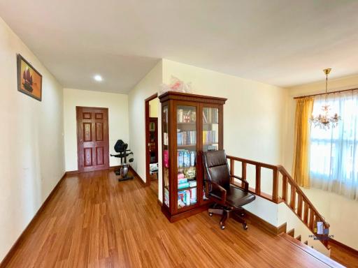 Spacious upper-level living area with hardwood floors, bookshelf, and natural light