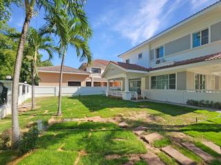 Spacious two-story house with large front yard and palm trees