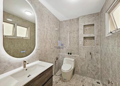 Modern bathroom with large mirror and neutral tile finish