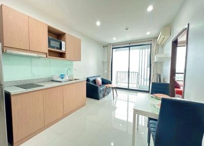 Modern kitchen with wood cabinets and integrated appliances leading to a cozy balcony