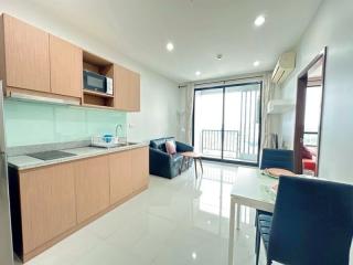 Modern kitchen with wood cabinets and integrated appliances leading to a cozy balcony