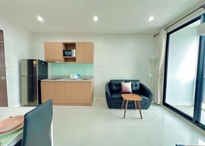 Compact living room with modern kitchenette, plenty of natural light, and sleek furniture