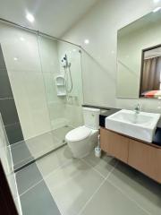 Modern bathroom with glass shower enclosure, toilet, and vanity