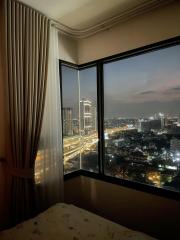 Bedroom with large window overlooking a city at night