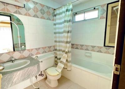 Clean tiled bathroom with shower curtain and natural light