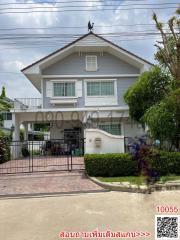 Exterior view of a two-story residential house with a manicured lawn and clear skies