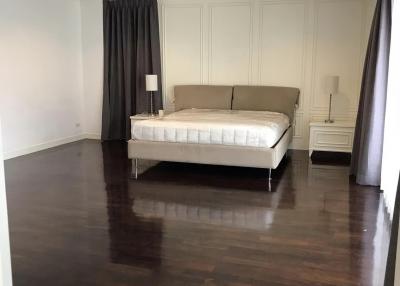 Spacious bedroom with a large bed, hardwood floors, and elegant drapes